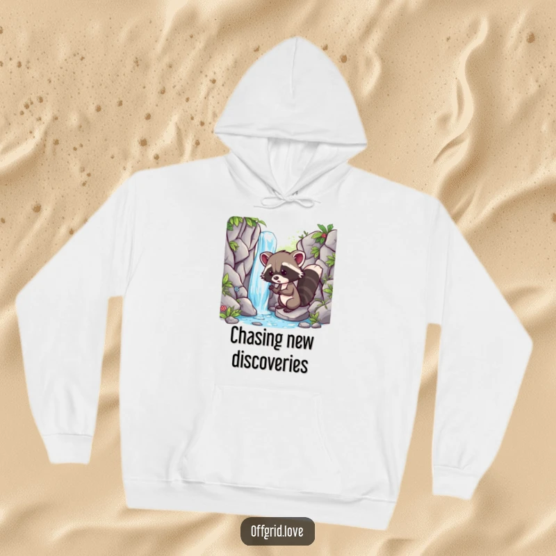 Funny hoodie featuring a mischievous racoon discovering a beautiful hidden waterfall, exuding a sense of wonder and fun.